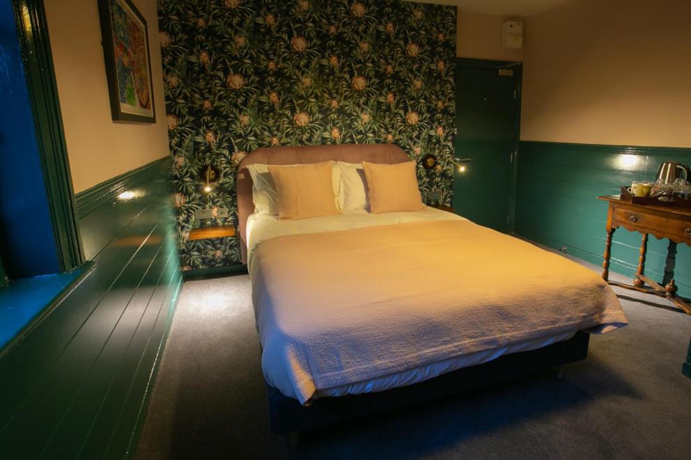 a bedroom with a large bed with a green wall at The Ship Rooms in London