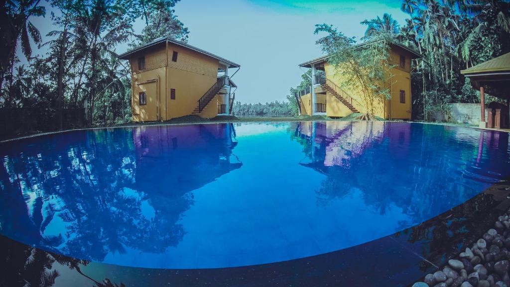 una grande piscina con acqua blu di fronte a due edifici di Amri River Cottages And Ayurvedee Retreat a Bentota