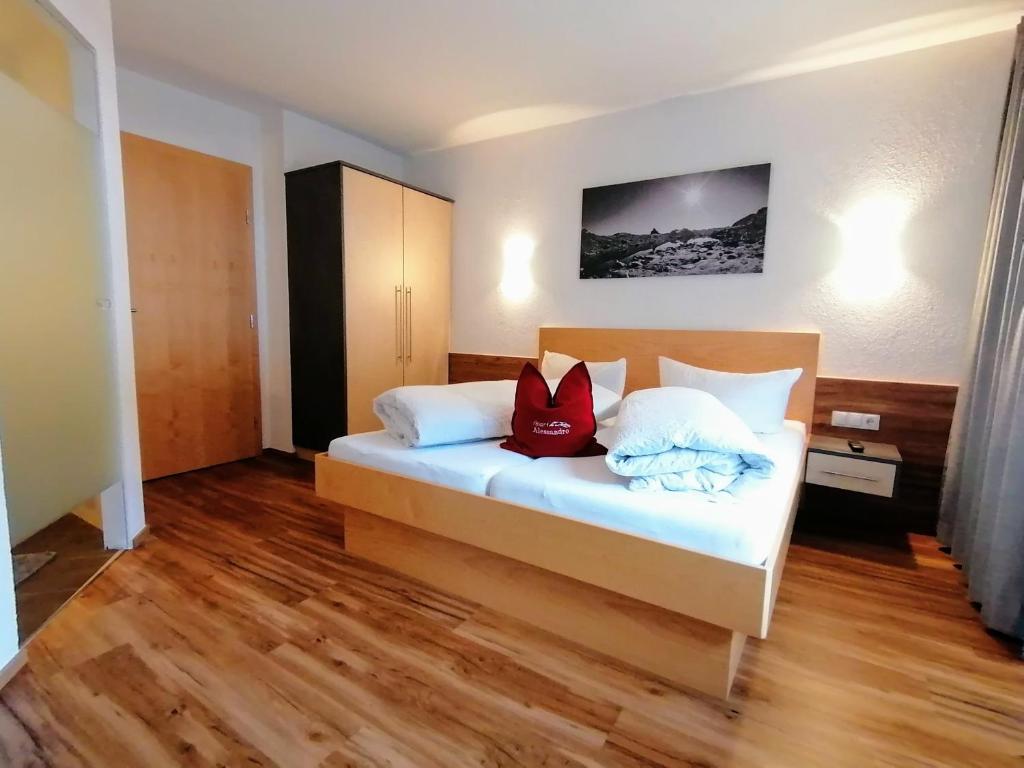 a bedroom with a bed with white sheets and red pillows at Apart Alessandro in Längenfeld