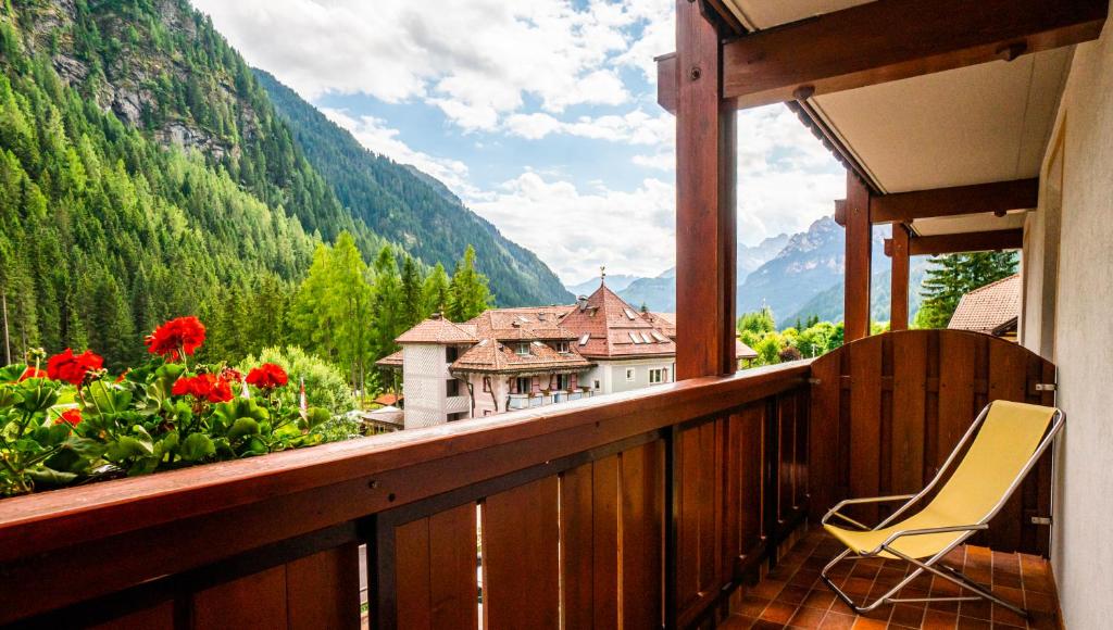 a chair on a balcony with a view of a house at Garni Aritz in Campitello di Fassa