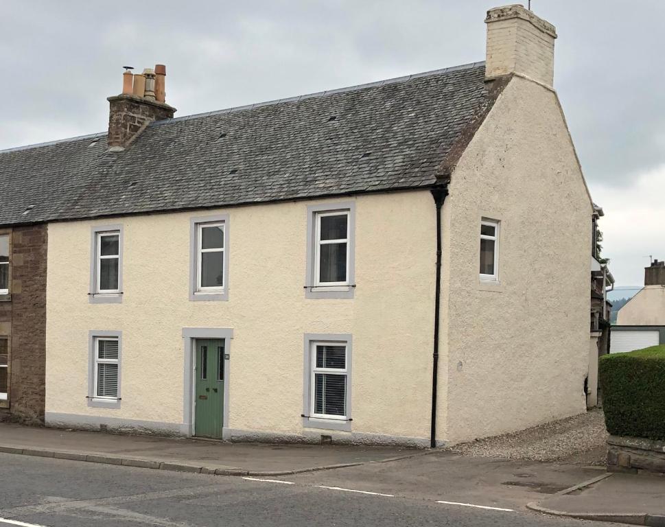 a white house with a green door on a street at Garron House in Auchterarder