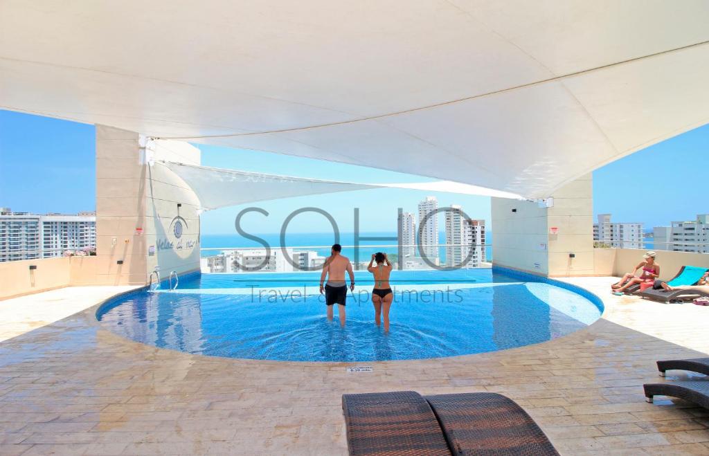 un hombre y una mujer parados en una piscina en un edificio en Apartamentos Velas al Mar - Cerca al Mar by SOHO, en Santa Marta