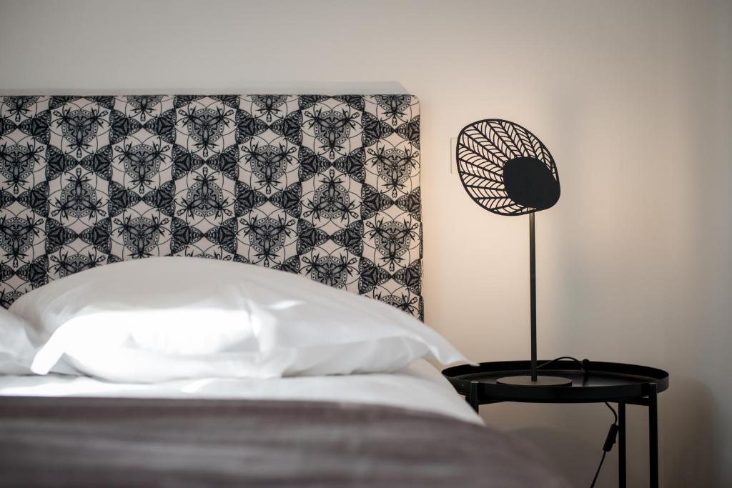 a bed with a black and white headboard and a lamp at Les apparts du marché in Obernai