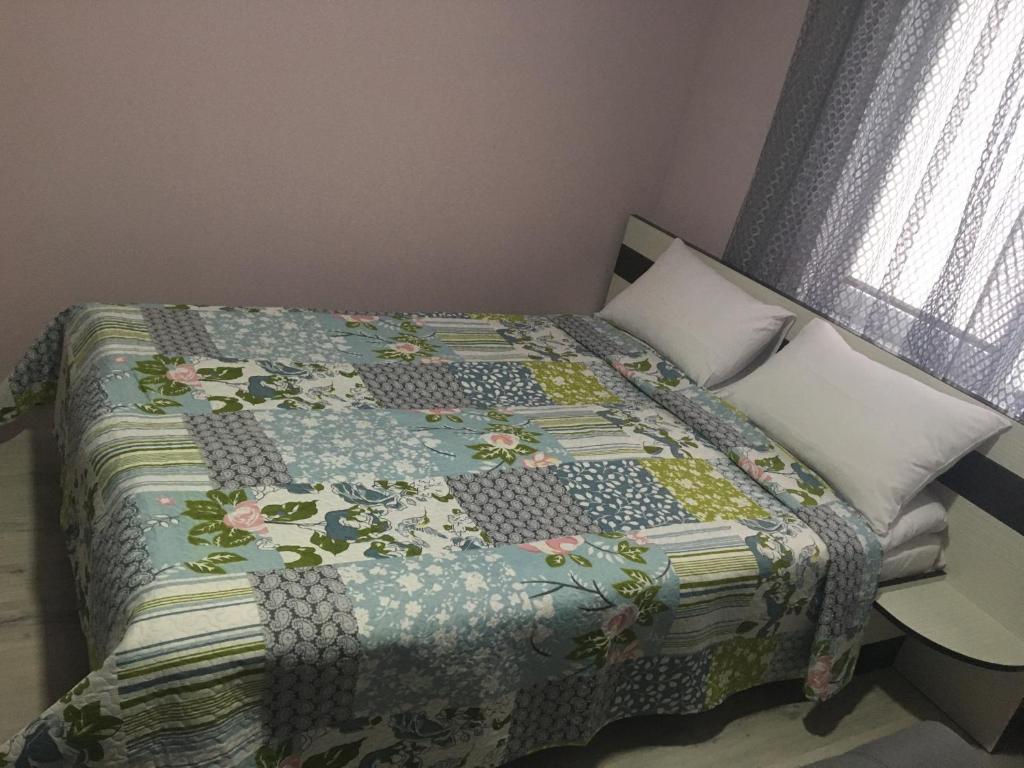 a bed with a quilt on it in a bedroom at Guest House MAX in Khmelʼnytsʼkyy