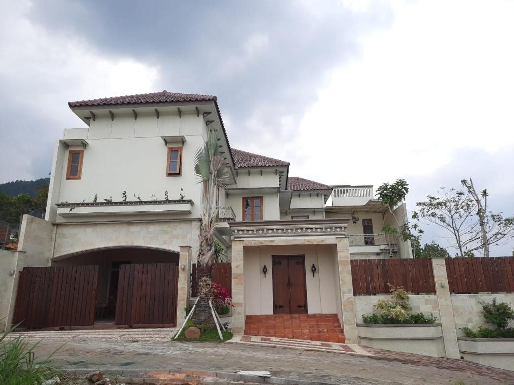 una casa blanca con una puerta y una valla en Villa Ayana Syariah en Batu