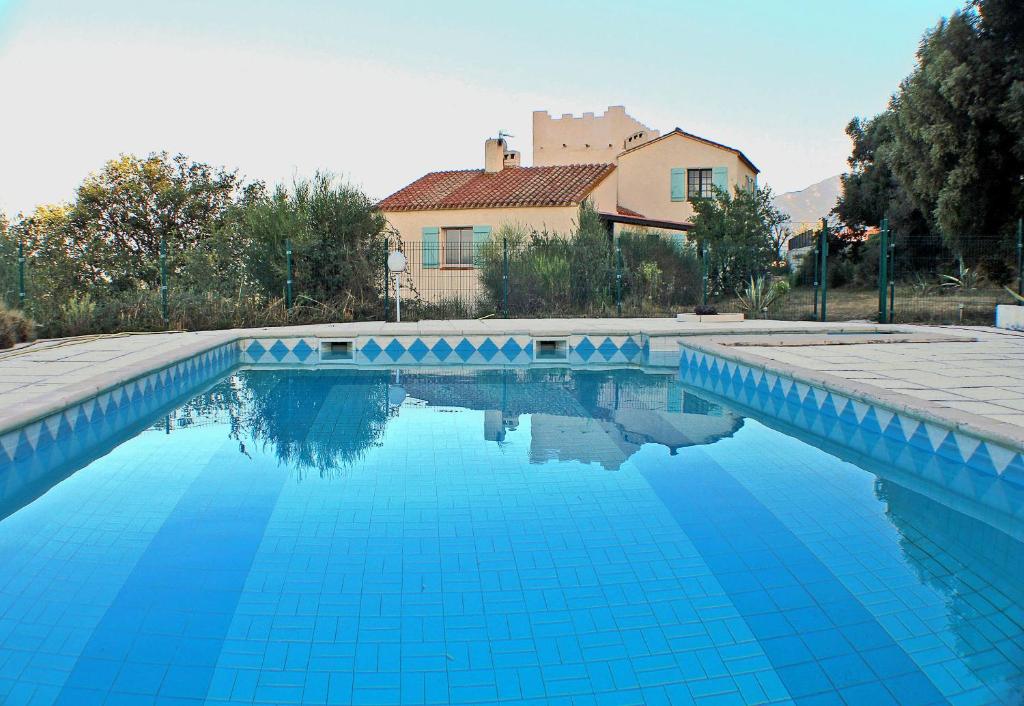 une piscine bleue avec une maison en arrière-plan dans l'établissement Mas Natura, à Banyuls-dels-Aspres