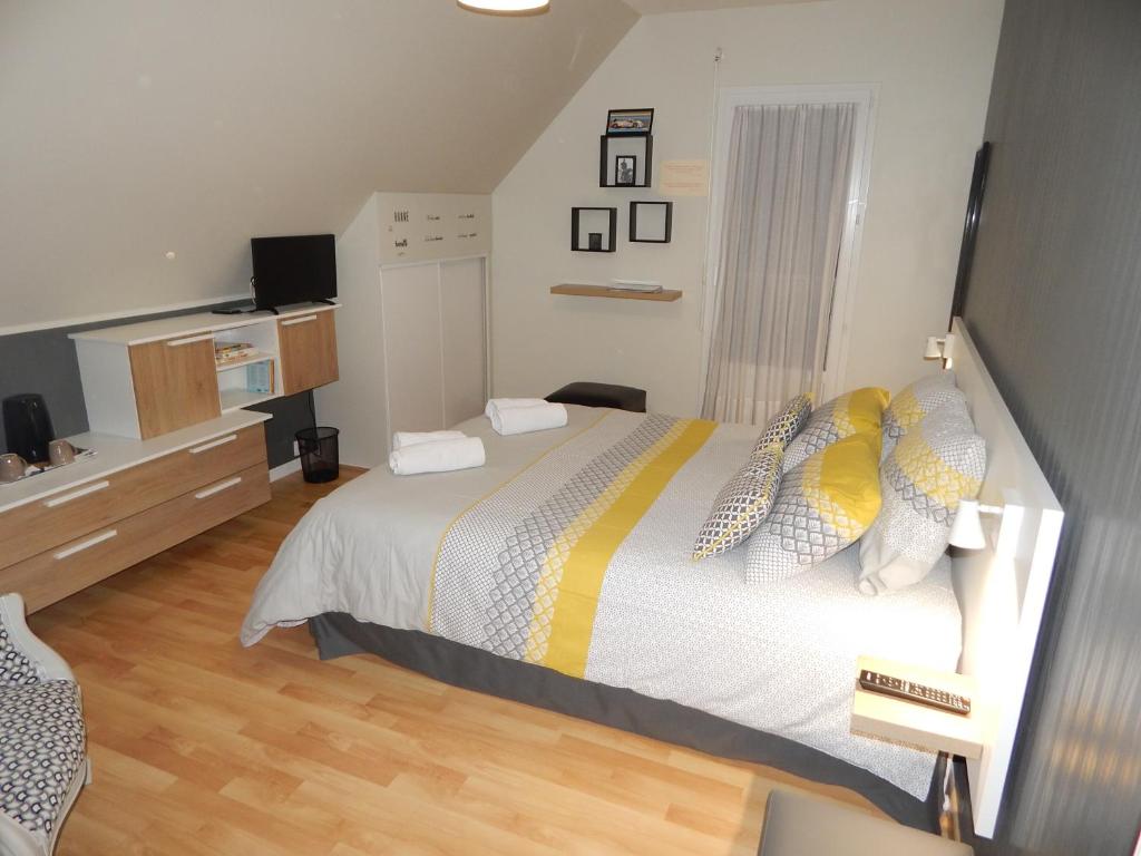 a bedroom with a large bed with yellow and white pillows at Audionnière in Saint-Gervais en-Belin
