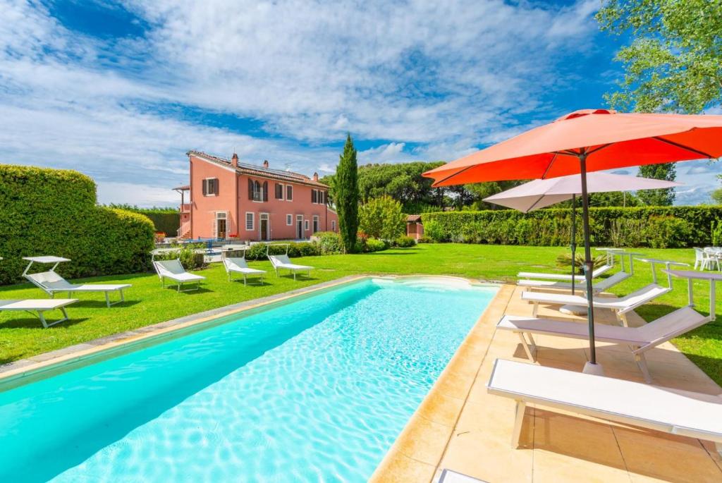 a pool with chairs and an umbrella next to a house at Villa Rossa in Pisa