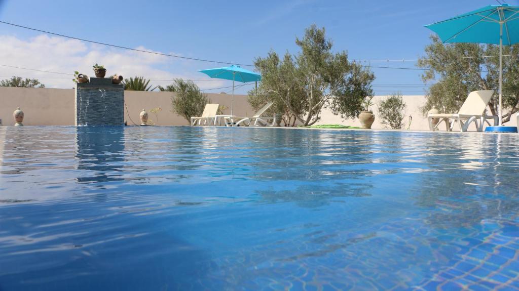 una piscina de agua azul en un complejo en villa la rose des sables en Midoun