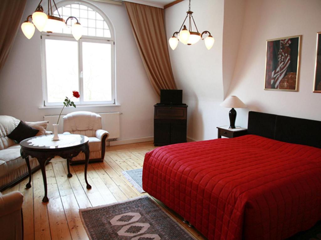 um quarto com uma cama vermelha e um sofá em Villa Ingrid em Veimar