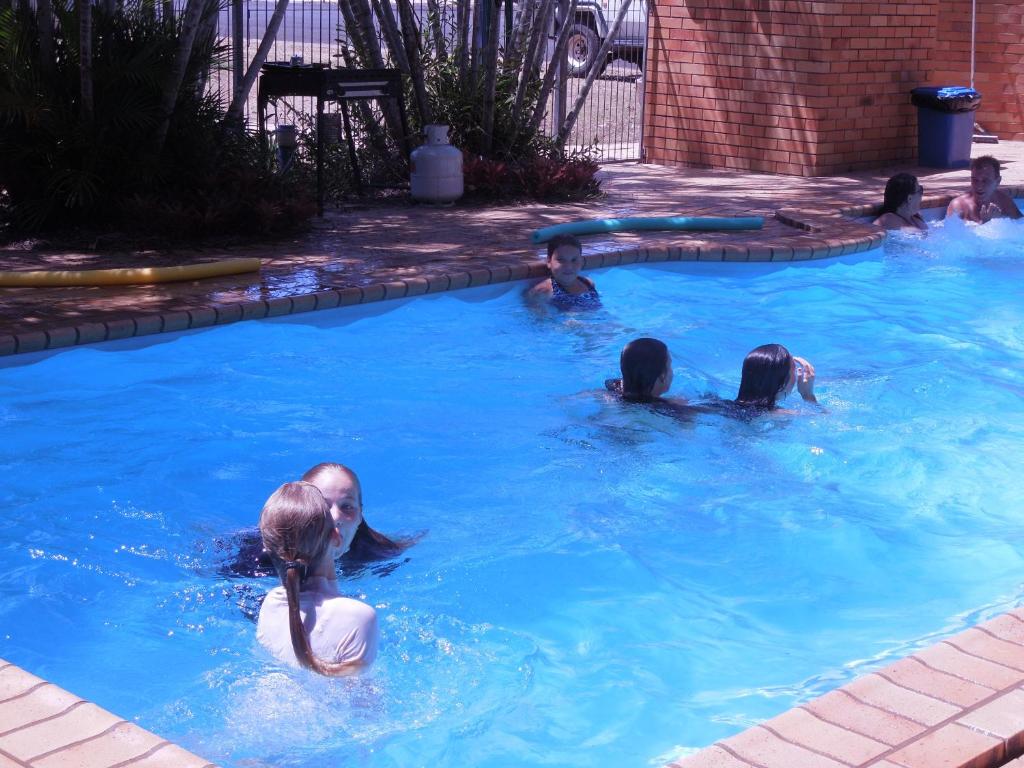 een groep mensen die zwemmen in een zwembad bij Moore Park Beach Inn in North Coast