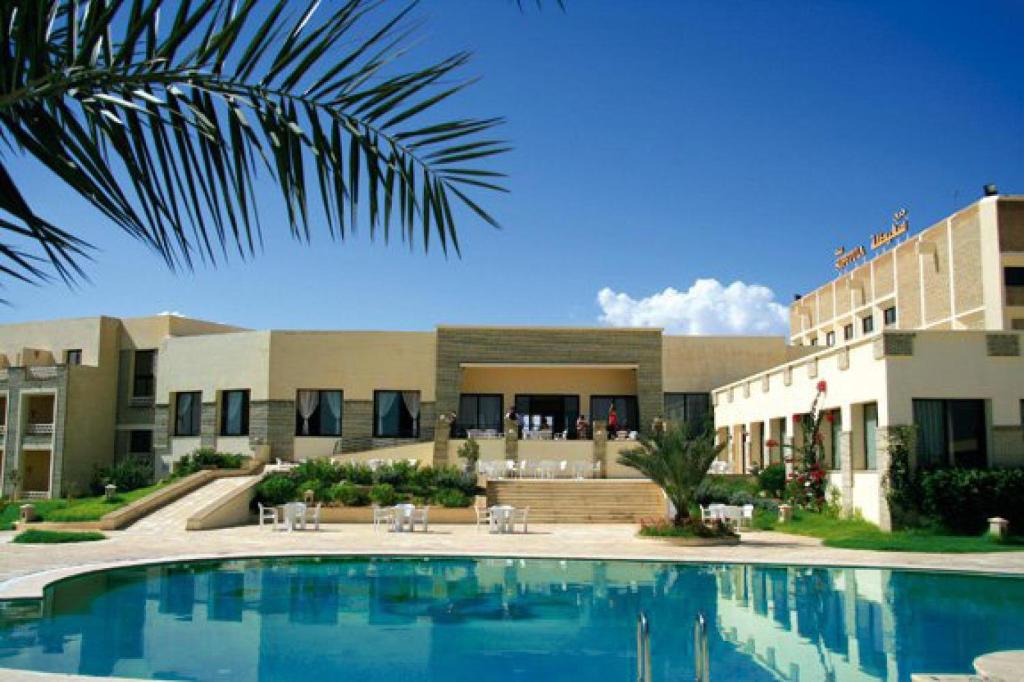 un complejo con piscina frente a un edificio en Sufetula Hotel en Sbeitla