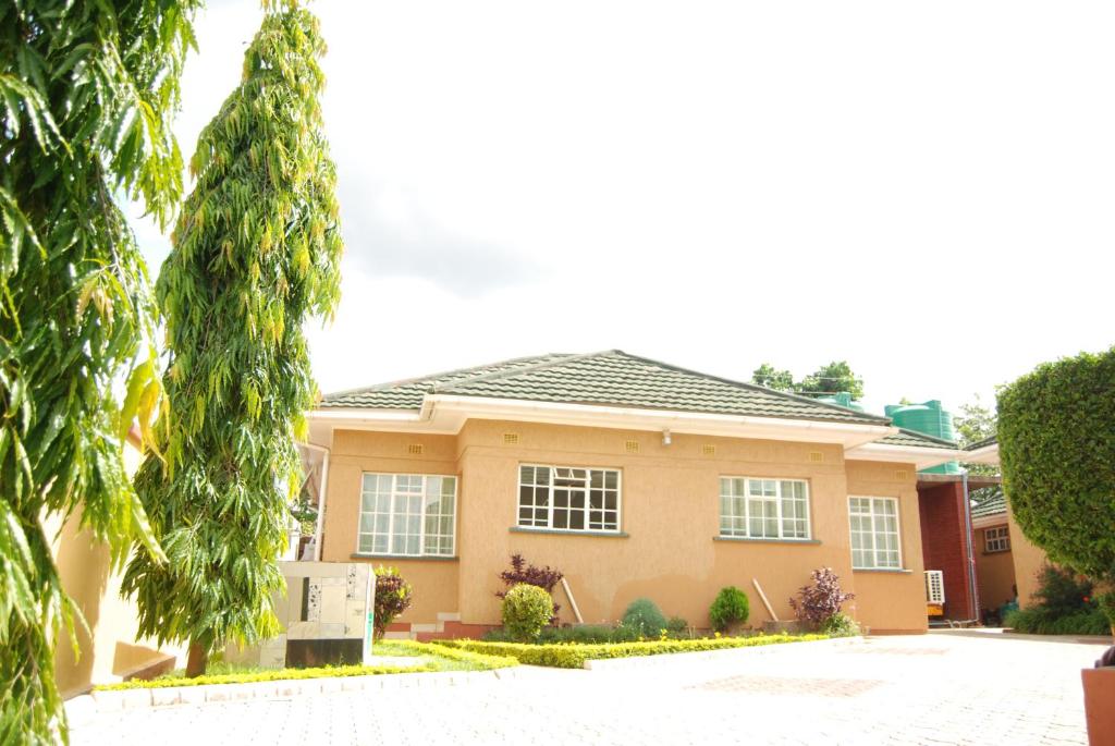 a yellow house with trees in front of it at Lonjeta Self-Catering Apartments in Lilongwe