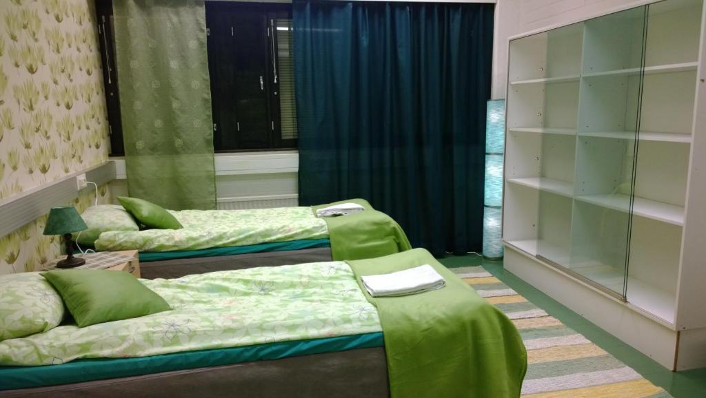 two beds in a room with green at Motel Ruskalinna in Pello
