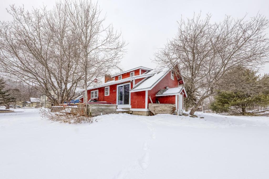 a red house with snow on the ground at Roxbury Retreat in Roxbury