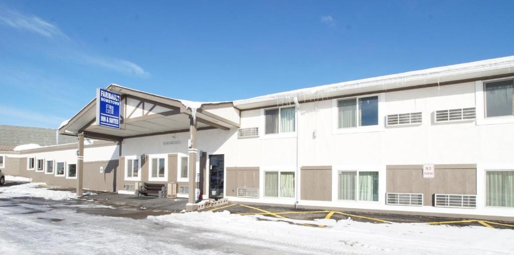 un edificio blanco con una señal azul delante de él en Faribault Hometown Inn & Suites, en Faribault