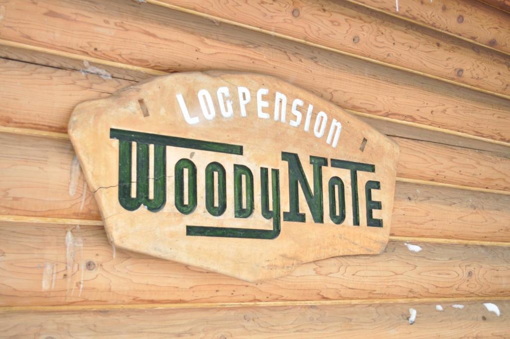 una señal en el lateral de una pared de madera en Pension Woody Note en Niseko