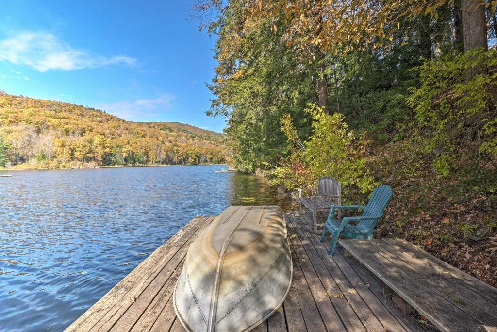 a dock with a boat and a chair on a lake at Lakefront Berkshires Retreat with Deck, Dock and Boat! in Great Barrington