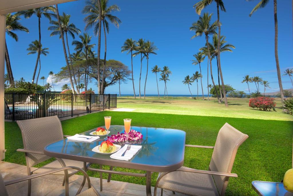 Gorgeous Oceanfront Condo with Spectacular Views! في كيهي: طاولة مع الطعام والزهور على الفناء مع أشجار النخيل