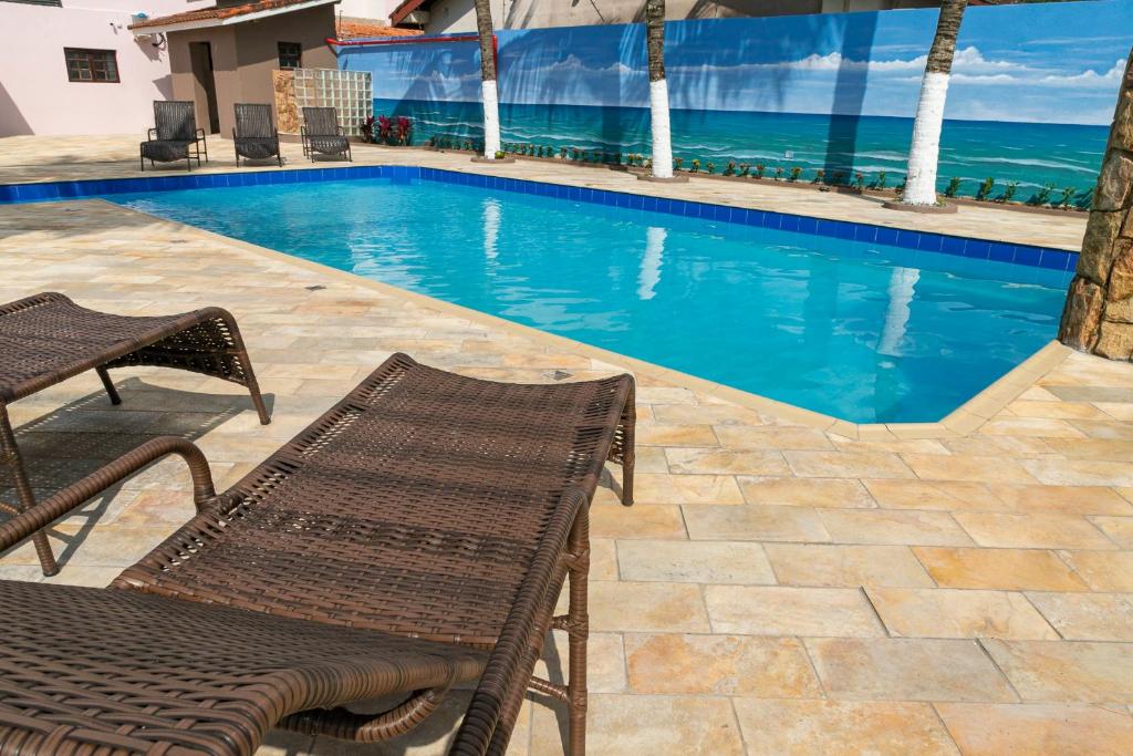 a swimming pool with a bench and the ocean at Namoa Pollastrini in Itanhaém