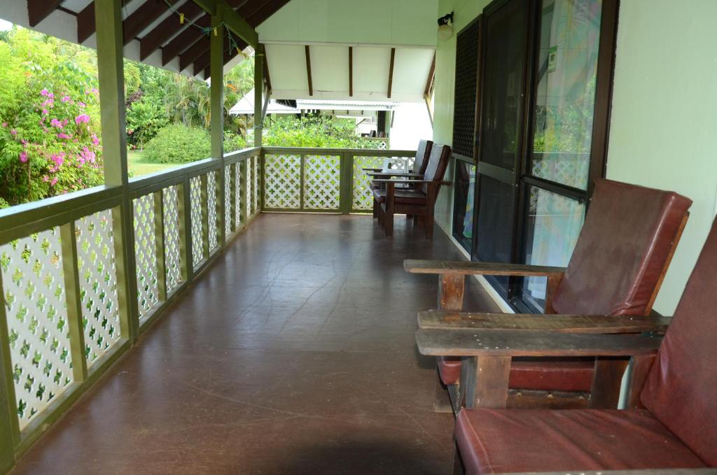 un porche con 2 sillas y un banco. en Gina's Garden Lodges en Arutanga
