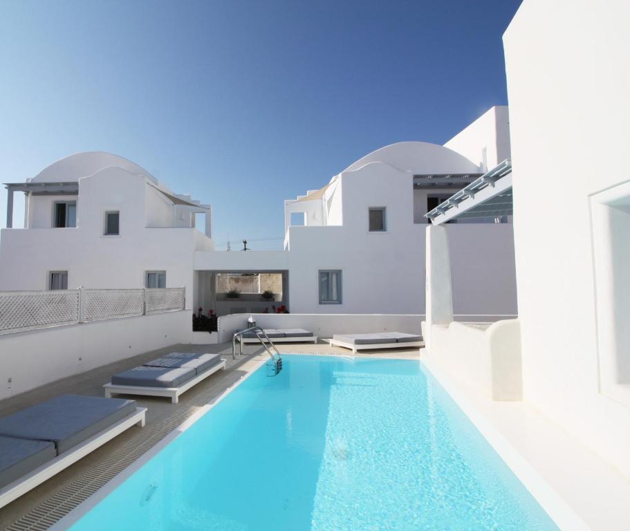 a large swimming pool with a blue and white tub at Palmariva Villas in Fira