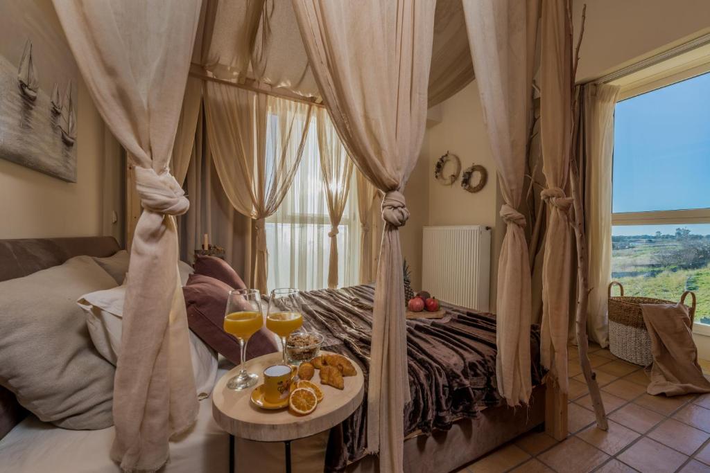 - une chambre avec un lit à baldaquin et une table avec des verres de jus d'orange dans l'établissement ARCHONTIKO VILLAGE VOLIMES 5' minutes from the shipwreck, à Volímai