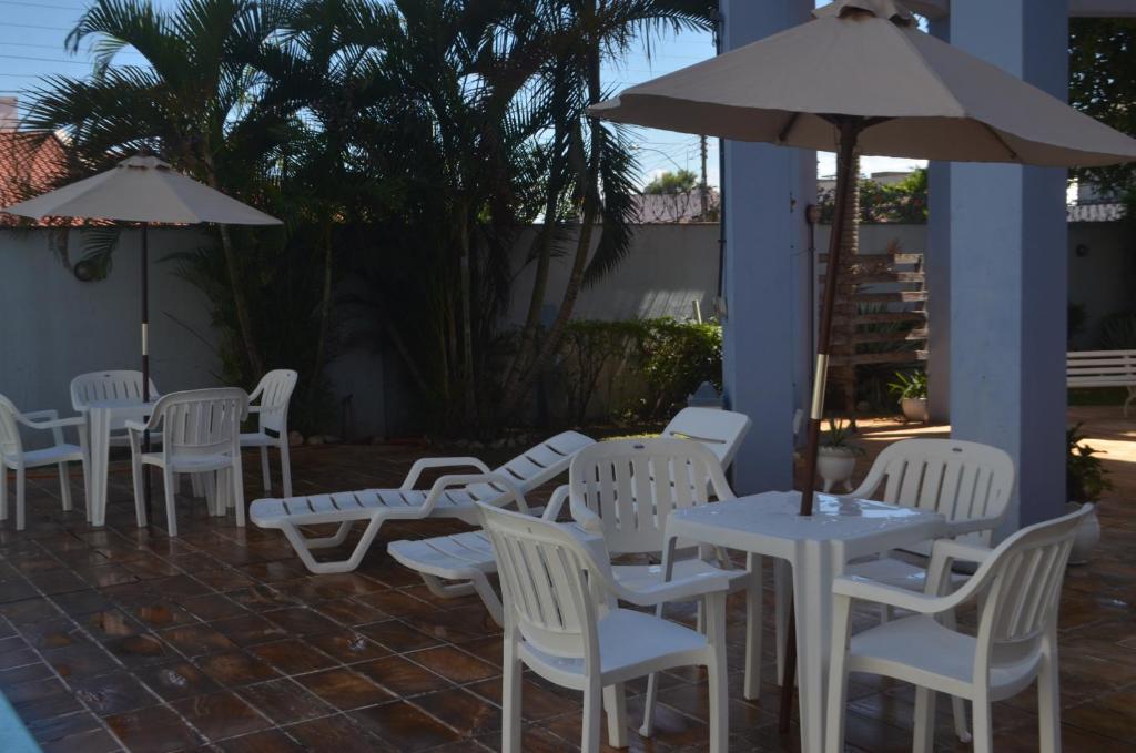 un grupo de mesas y sillas blancas y una sombrilla en Hotel Obino São Borja, en São Borja