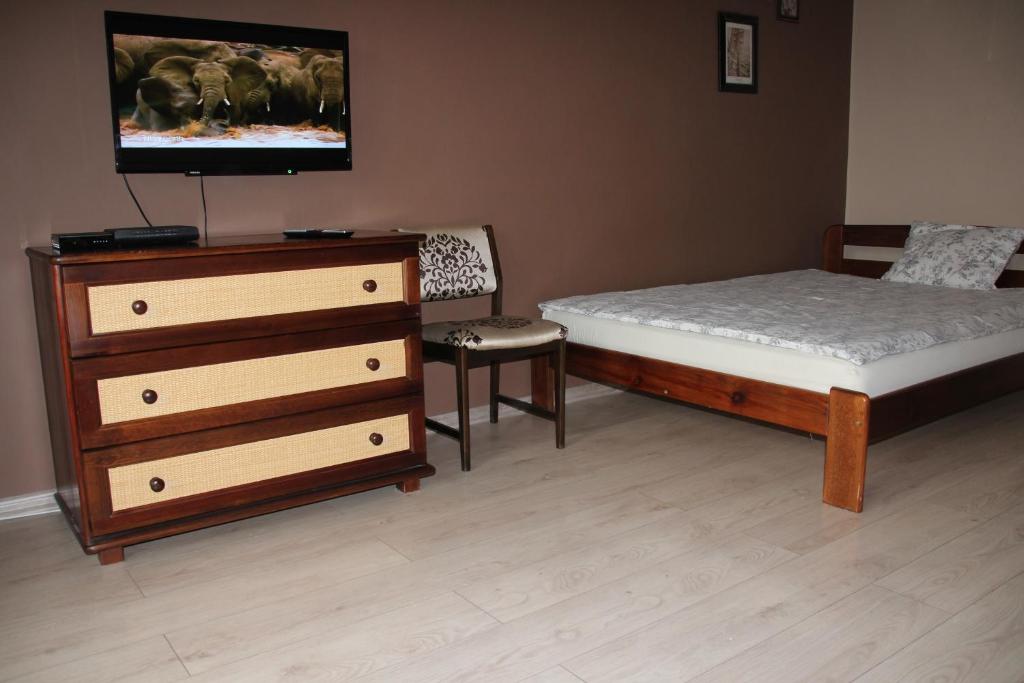 a bedroom with a bed and a dresser with a tv at Apartment Widok in Kraków