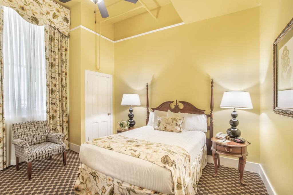 a bedroom with a bed and a chair at Menger Hotel in San Antonio
