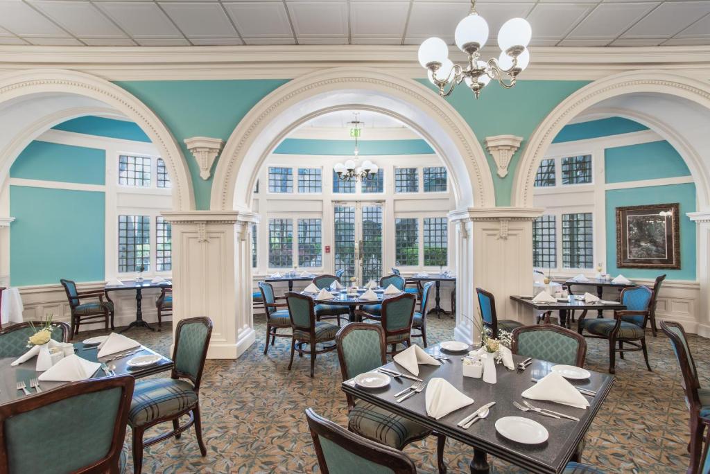 a dining room with tables and chairs and windows at Menger Hotel in San Antonio