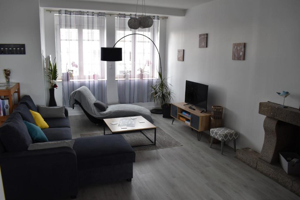 ein Wohnzimmer mit einem Sofa und einem TV in der Unterkunft Gîte de la Roche - Grande maison bretonne in Lannilis