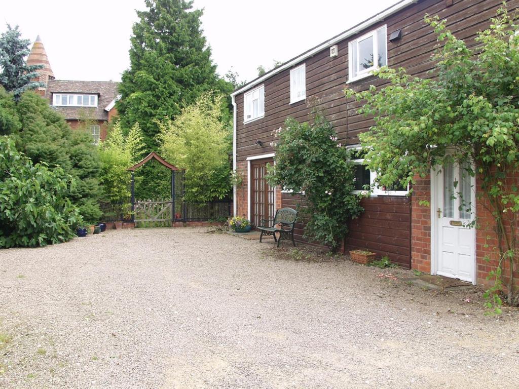 una casa con una entrada de grava junto a un edificio en The Coach House, en Ledbury