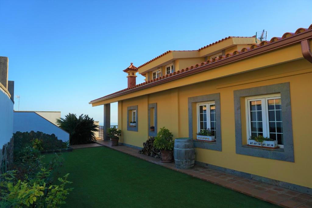 a yellow house with a green lawn at Pedro's house with fantastic views in Telde