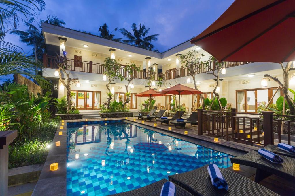 a swimming pool in front of a house at Puri Payogan Villa in Ubud
