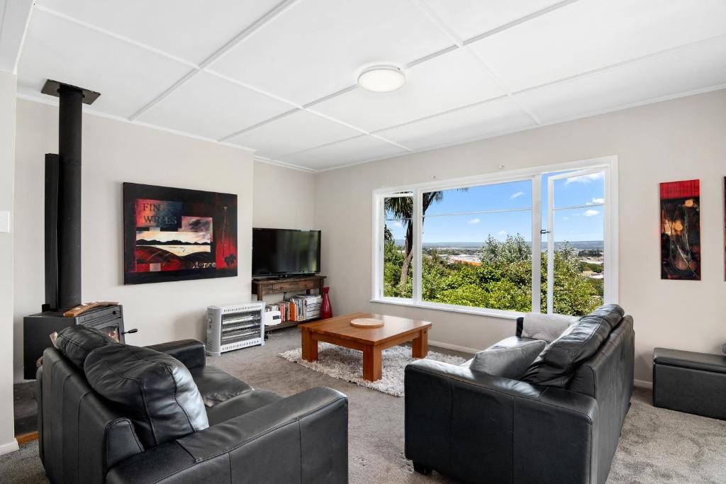 uma sala de estar com mobiliário de couro preto e uma grande janela em Great Tasman Outlook - Nelson Holiday Home em Nelson