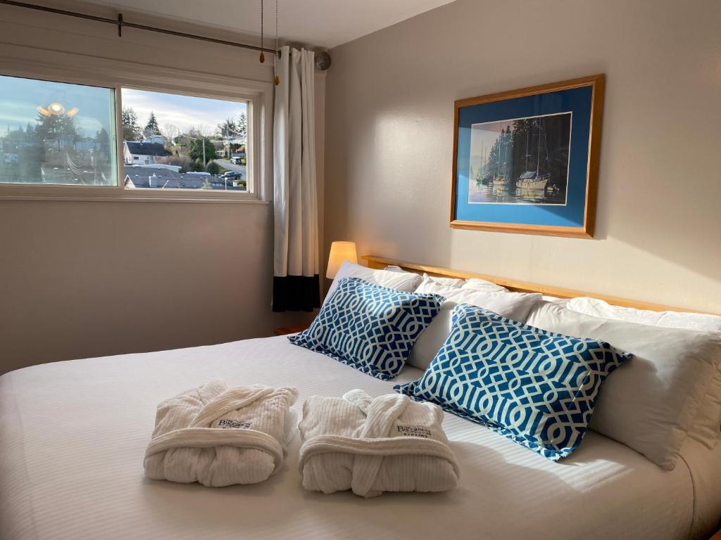 a bedroom with a white bed with blue and white pillows at Buccaneer Inn in Nanaimo