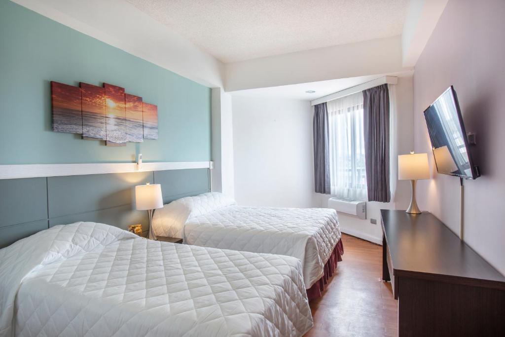 um quarto de hotel com duas camas e uma televisão de ecrã plano em Grand Plaza Hotel em Tumon