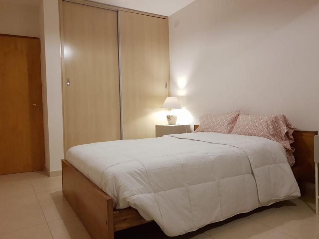 a bedroom with a large white bed and a lamp at Rivadavia Aparts in San Rafael