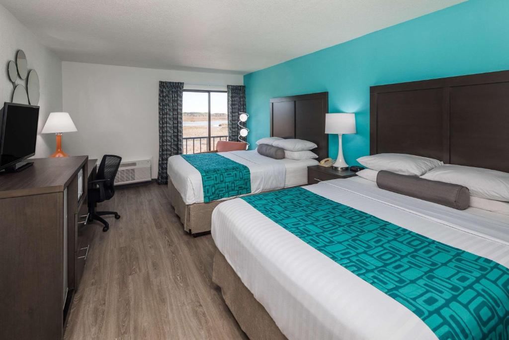 a hotel room with two beds and a flat screen tv at Howard Johnson by Wyndham Beaufort/Parris Island in Beaufort