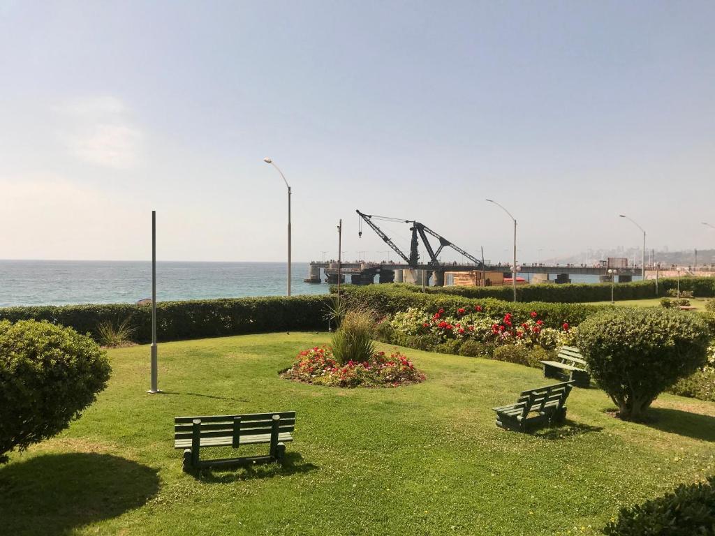 dos bancos sentados en un parque cerca del océano en Departamento en Playa Acapulco viña del mar, en Viña del Mar