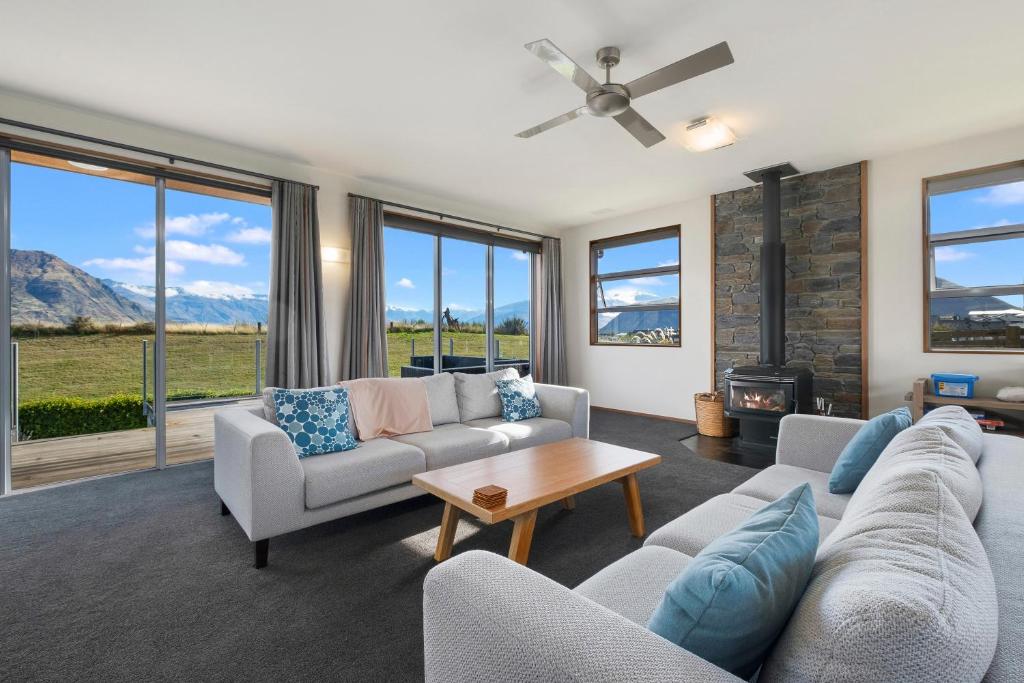 ein Wohnzimmer mit Sofas und einem Kamin in der Unterkunft Infinity Views - Modern Wanaka Holiday Home in Wanaka