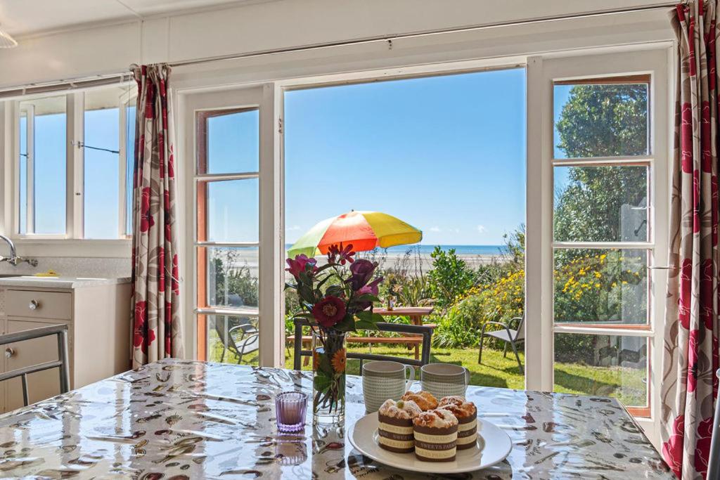 a kitchen with a table with a view of the ocean at Pakawau Beach House - Golden Bay Holiday Home in Pakawau