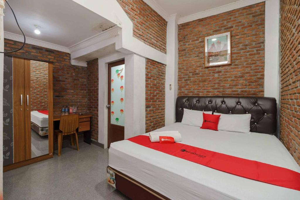 - une chambre avec un grand lit et un mur en briques dans l'établissement RedDoorz Syariah near Jalan Asahan Pematang Siantar, à Pematang Siantar