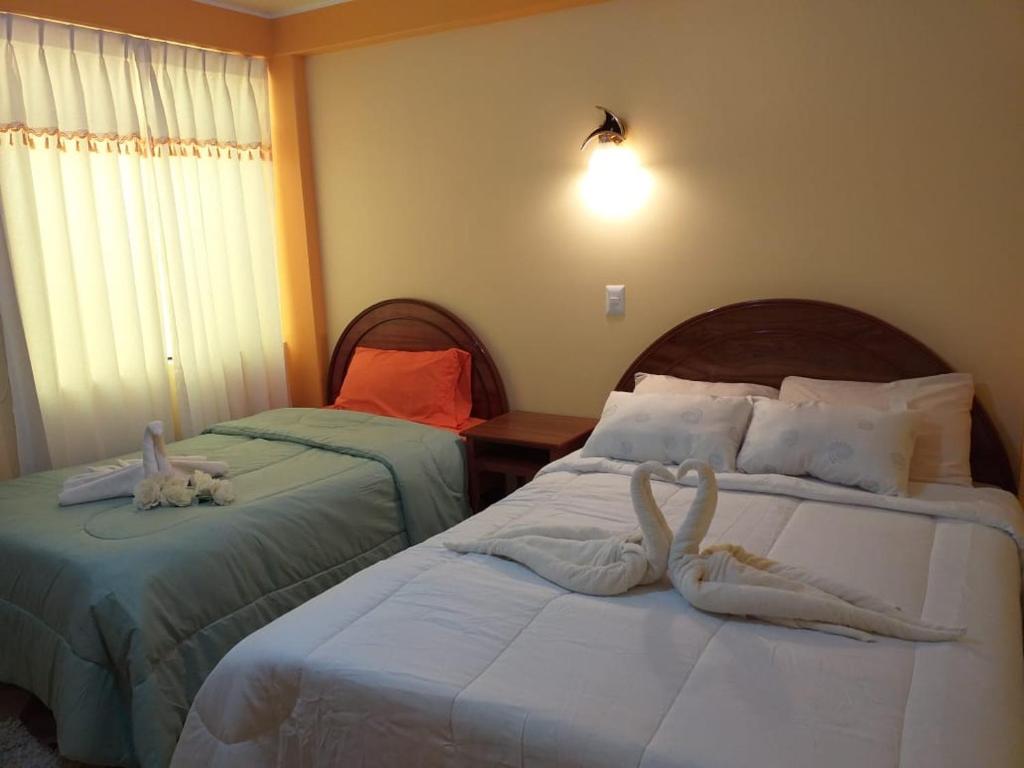 Dos camas en una habitación de hotel con animales de peluche. en Hostal Real Divina, en Juliaca
