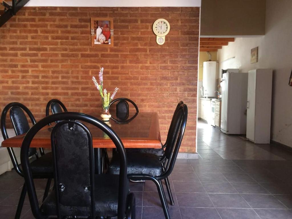 mesa de comedor con sillas negras y pared de ladrillo en Altas Mareas 1 en Las Grutas