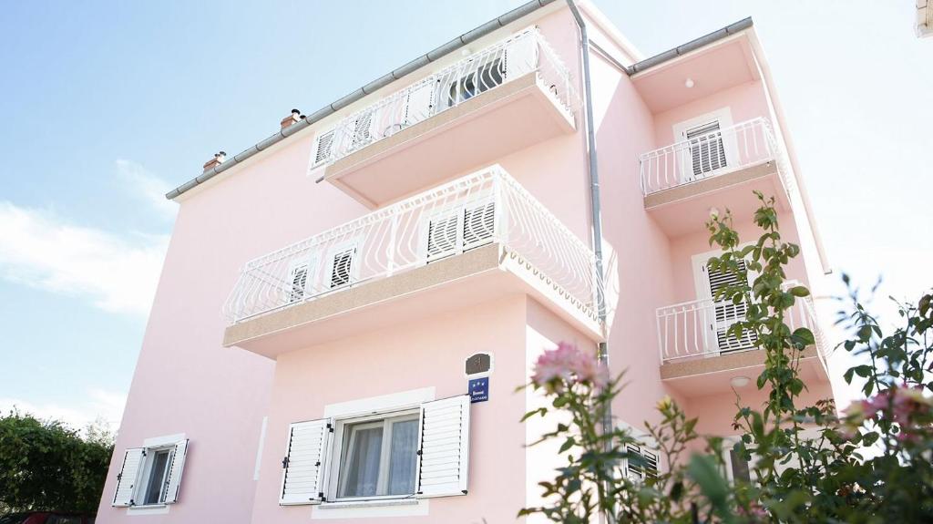 - un bâtiment rose avec des balcons blancs dans l'établissement Ivic Apartments Vodice Croatia, à Vodice