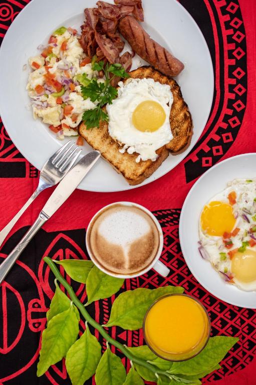a plate of breakfast food with eggs bacon and a cup of coffee at Zanzibar Queen Hotel in Matemwe