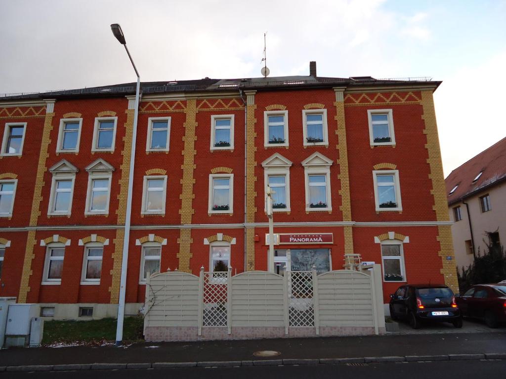 um edifício de tijolos vermelhos com uma cerca branca em frente em Pension Dresdener Panorama em Dresden