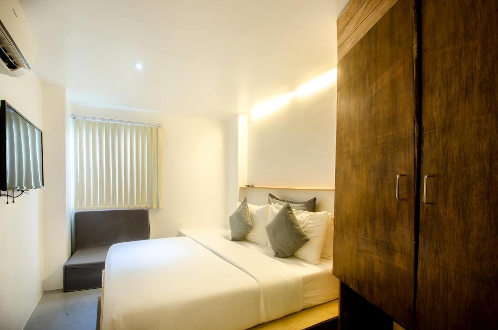 1 dormitorio con 1 cama blanca y 1 silla en Zuzuni Boutique Hotel, en Boracay